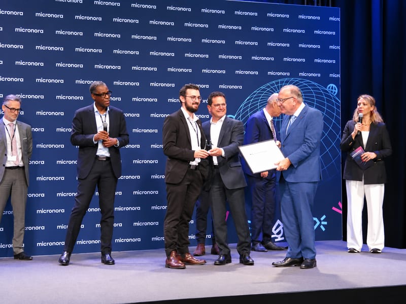 Award ceremony on the Micronora Awards stage: winners receive their trophy and certificate in front of a Micronora-branded backdrop